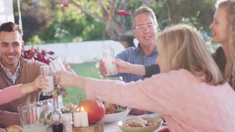 video de padres caucásicos felices, hija y abuelos haciendo un brindis en una mesa de cena al aire libre