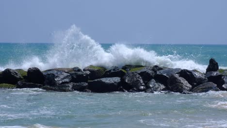 slow motion of frothy water ocean waves crashing and splashing over rocky stone seawall in southern sri lanka