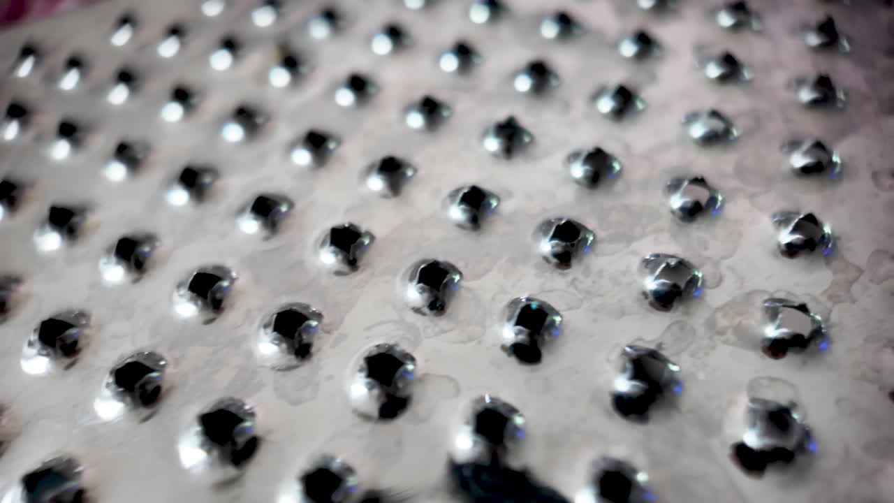 Close-up view of shiny cheese grater with sharp metal holes
