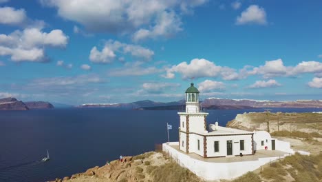 4k aerial drone orbit flying around beautiful lighthouse santorini greece with blue sky and clouds