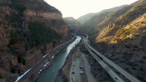 aerial drone flying backwards in a canyon with a highway, river and flying higher up as the shot goes on