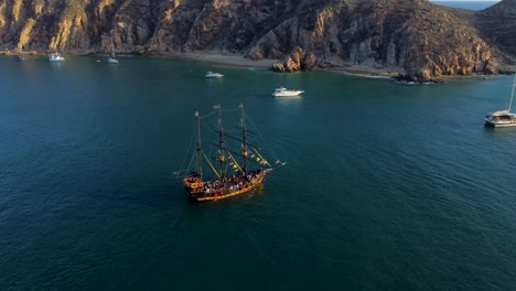 pirate ship in the middle of the sea, near some mountains at sunset