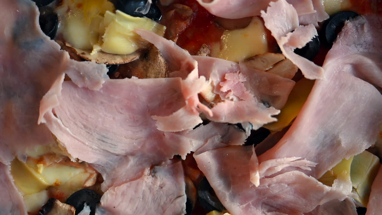 Primo piano di pizza appena sfornata condita con prosciutto, olive, funghi e formaggio