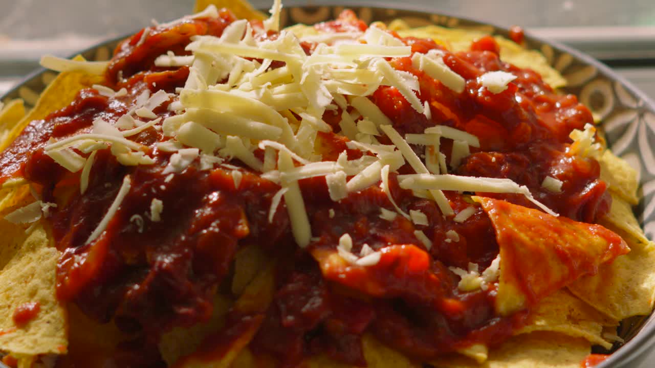 Pieces of Cheese Falling Down in Slow Motion on Nacho Tortilla Chips with Spicy Bean Salsa. Tex-Mex Party Mexican Snack Food