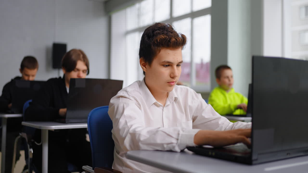 adolescentes en un aula usando computadoras portátiles