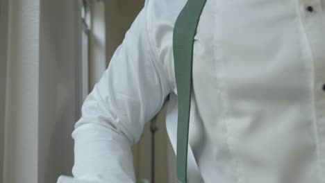 Groom-getting-ready,-putting-on-suspenders-on-his-wedding-day