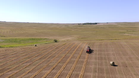 Tractor-Empacando-Heno---La-Empacadora-De-Heno-Recoge-Heno-Y-Hace-Rollos-De-Heno-En-Un-Día-Soleado-En-Saskatchewan,-Canadá