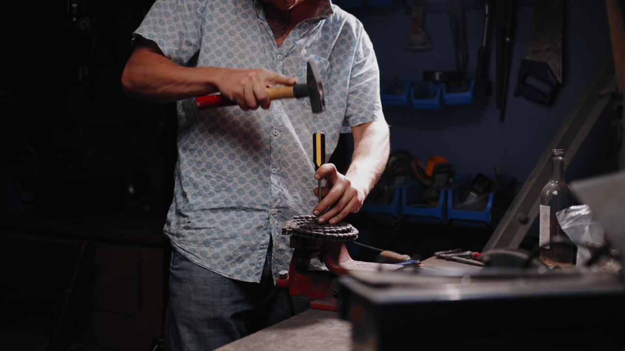 Cinematic shot of mechanic breaking a chain open with a screwdriver