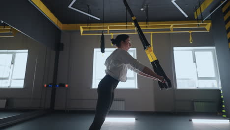 sporty woman doing trx exercises in the gym. women training with fitness straps in the gym. beautiful lady exercising her muscles sling or suspension straps.