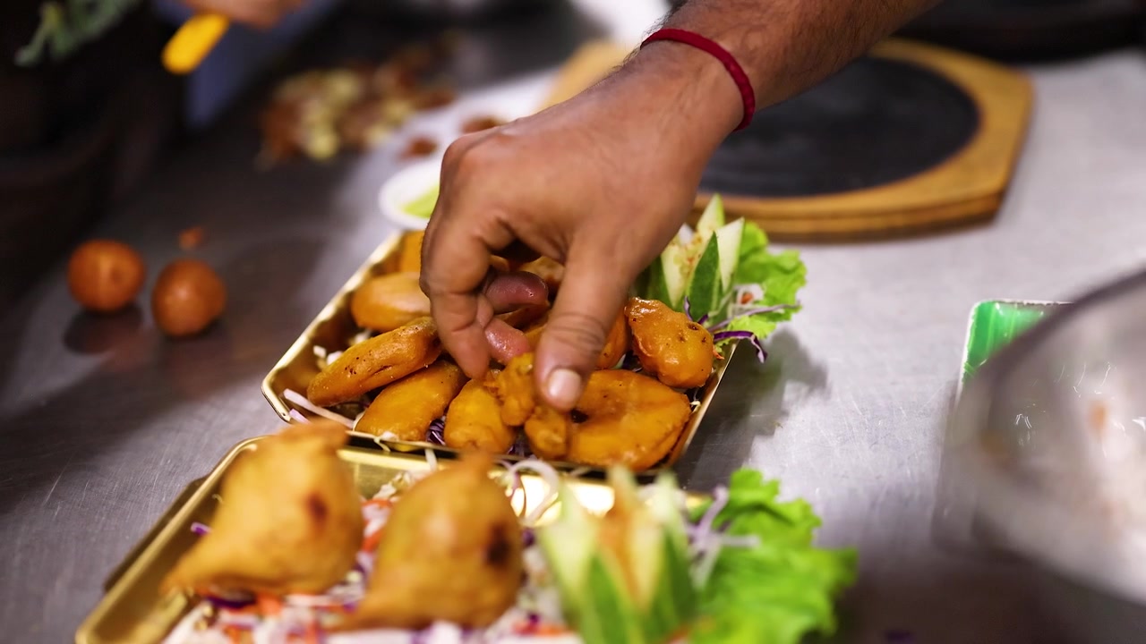 Chef che sistema snack indiani fritti su un vassoio da portata
