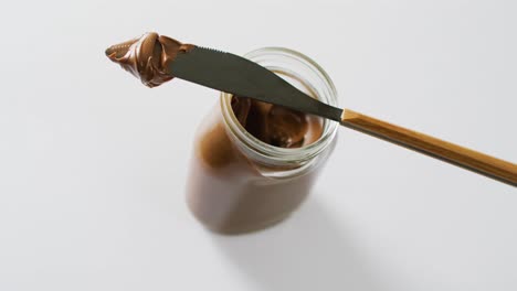 video de primer plano de un frasco de crema de chocolate sobre un fondo blanco