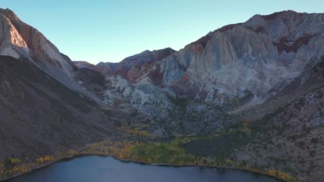 mammoth mountain lakes convict canyon lake aerial drone california autumn fall later afternoon shaded rugged valley peaks yellow aspen birch trees clear skies sierra nevada range windy forward motion
