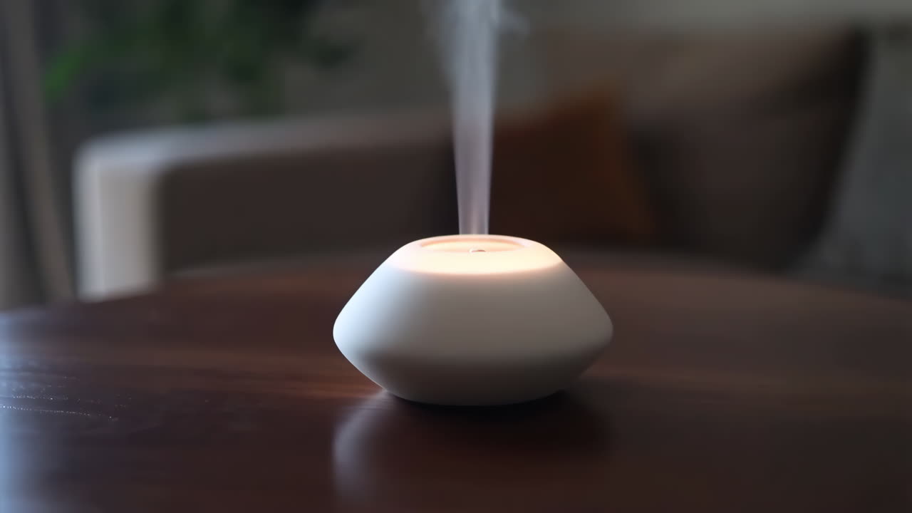 Diffuseur d'huiles essentielles émettant de la brume sur une table