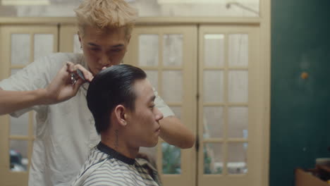 young asian man getting haircut in barbershop