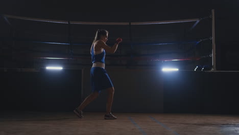 Beautiful-woman-fighter-in-red-bandages-conducts-a-shadow-fight-while-exercising-in-the-gym.-Slow-motion.-steadicam-shot