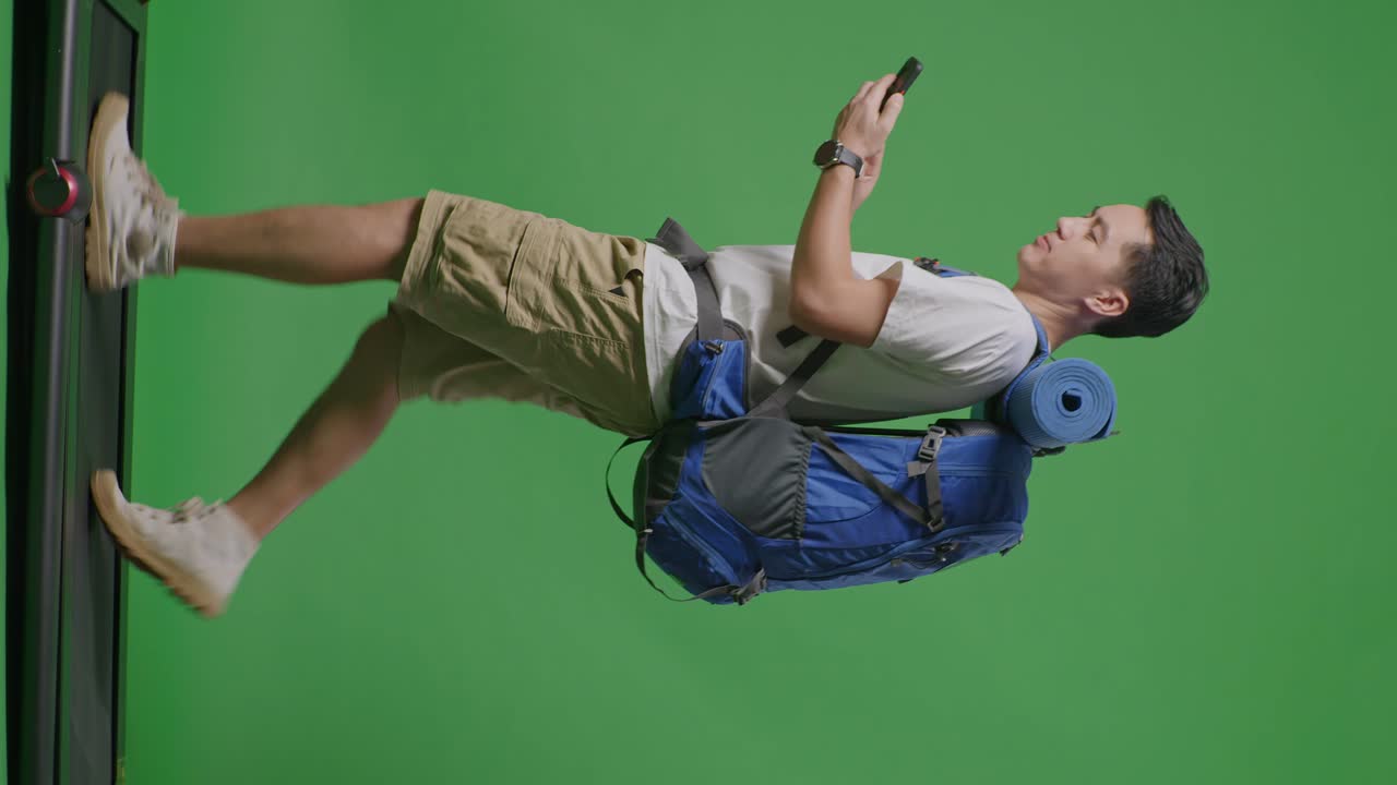 hombre con mochila en la cinta de correr contra la pantalla verde