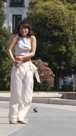 woman performing dance on footpath in city park during sunny day