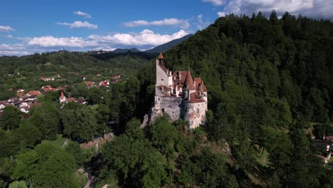 scenic aerial shot slowly orbiting around bran castle. medieval architecture among the green hills and forests of transylvania.