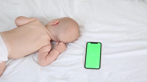 sleeping baby infant on white sheets with green screen chromakey device