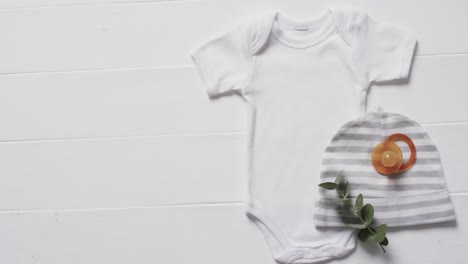 video of white baby grow, hat and dummy with copy space on white background