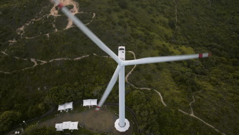 Aerial-top-down-shot-of-fast-spinning-wind-turbine-in-green-landscape-of-Lamma-Island