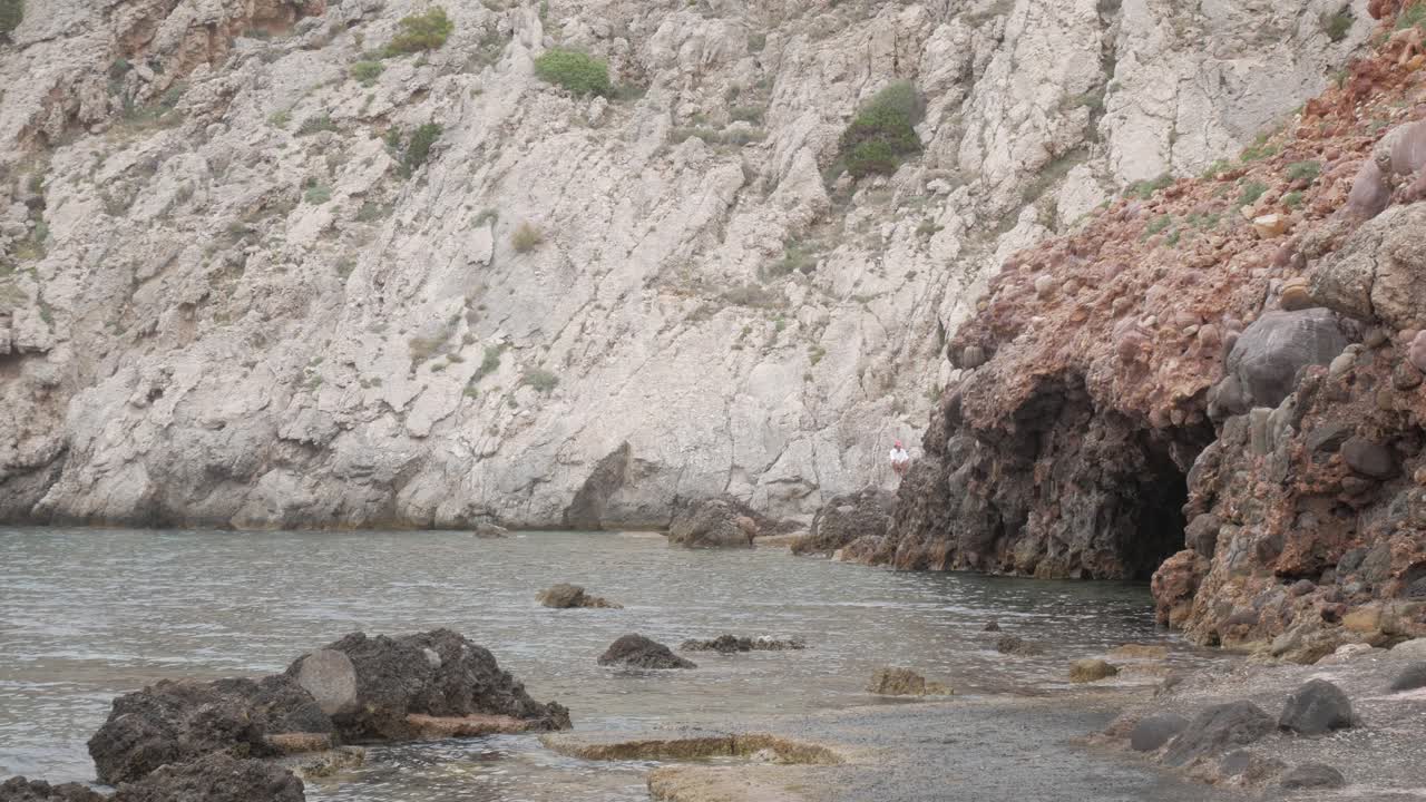 Rocky coastal cave with clear water at Cala Morell, evoking solitude and adventure