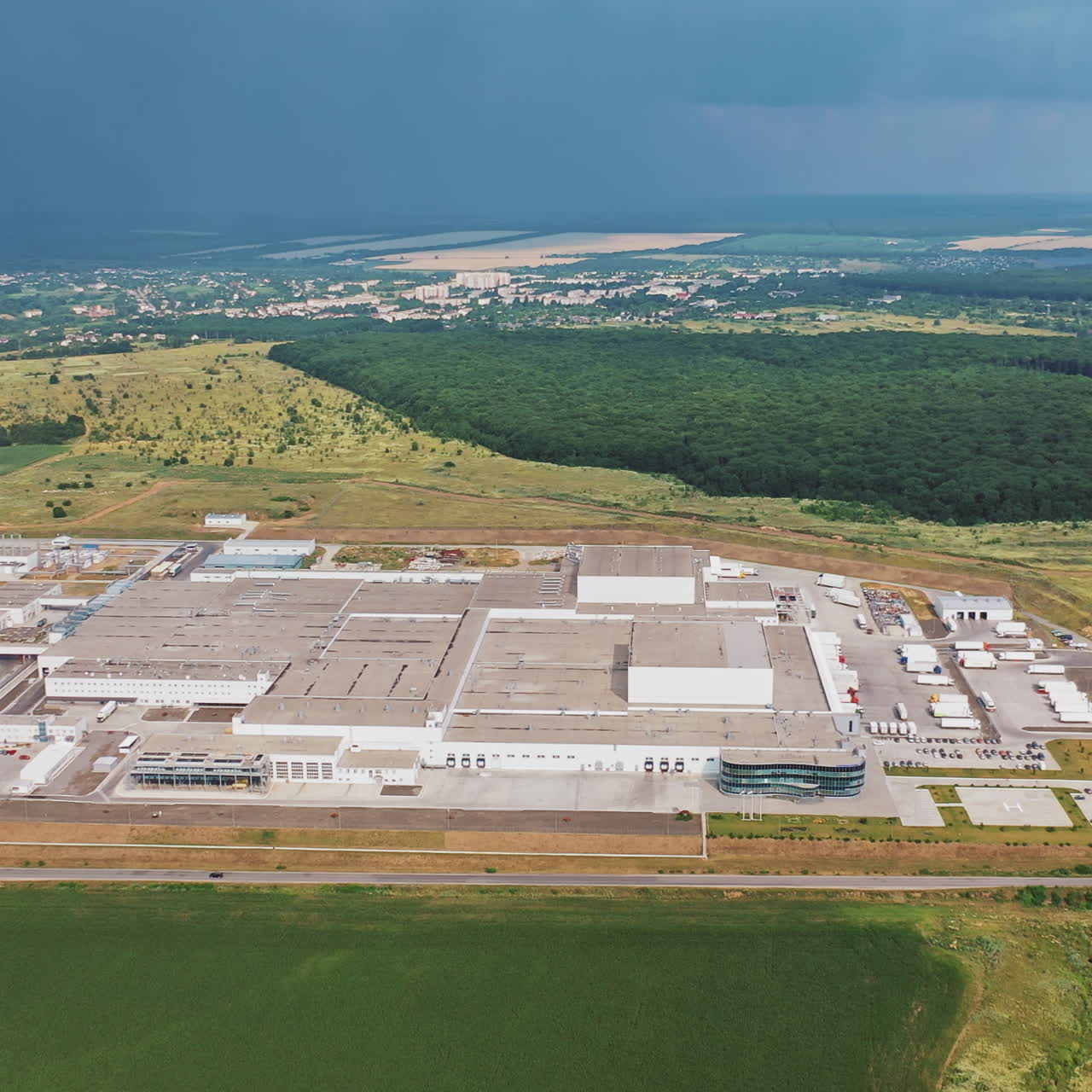 Aerial view of modern industrial building surrounded by green fields. Large modern production plant
