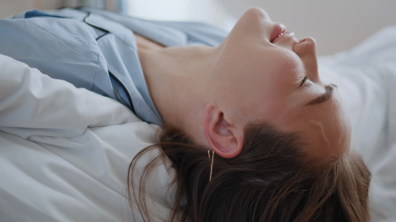 Morning girl lying bed touching hair closeup. Lazy model woman waking up resting