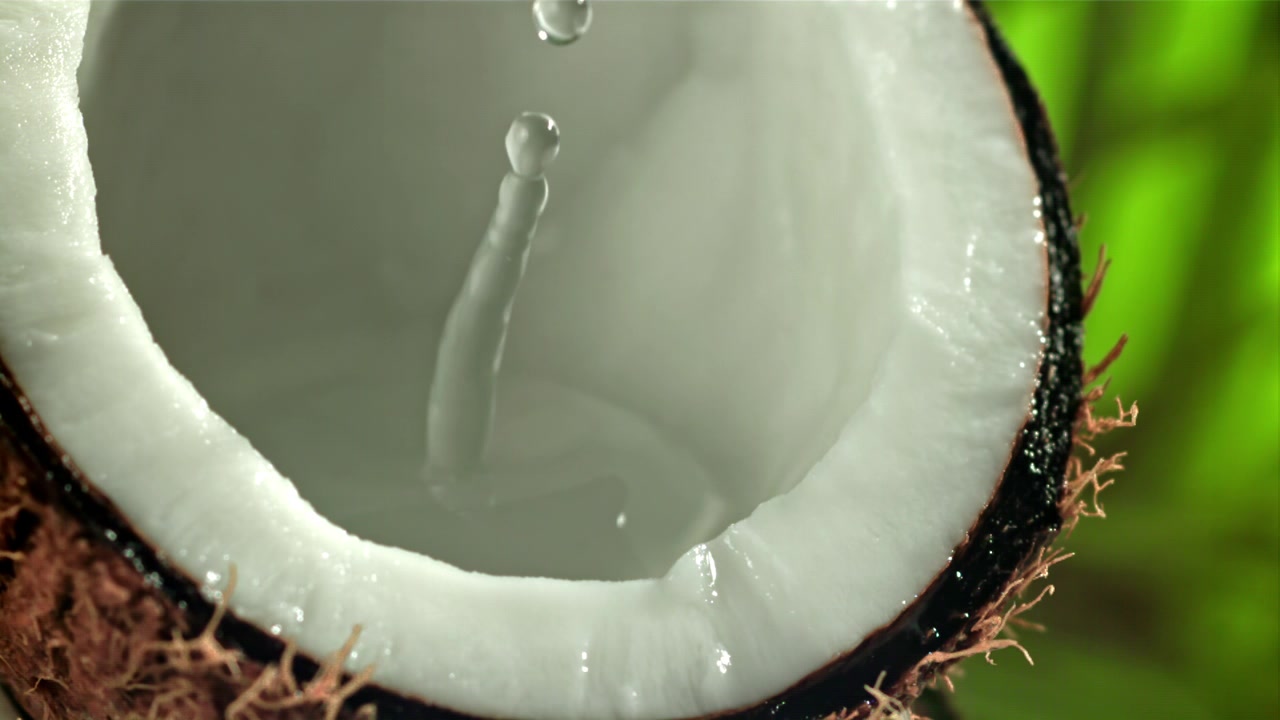 Close-up of Coconut Water Pouring into a Fresh Halved Coconut