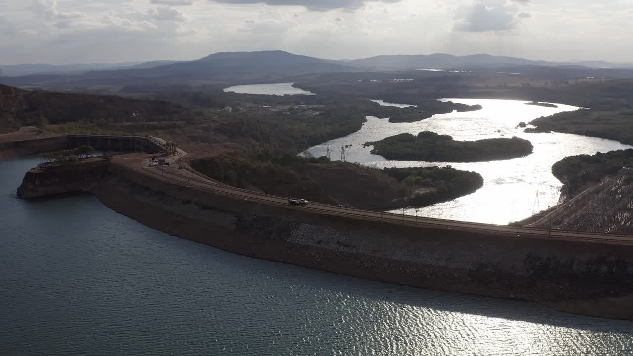 Aerial drone shot of cars passing by the Furnas Dam, a hydroelectric in Minas Gerais, Brazil, during a sunny day
