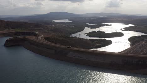 aerial drone shot of cars passing by the furnas dam, a hydroelectric in minas gerais, brazil, during a sunny day