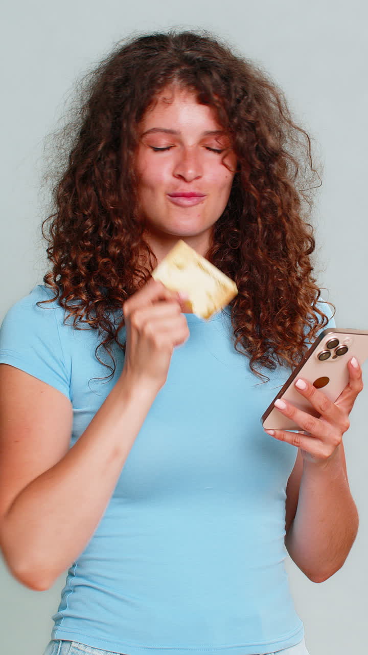 Woman smiling holding credit card smartphone showing online shopping success satisfied happy buyer