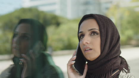 close-up of muslim woman in hijab talking on cellphone outdoors.