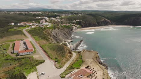 long aerial shot of a coastal village with a beautiful secluded beach surrounded by cliffs