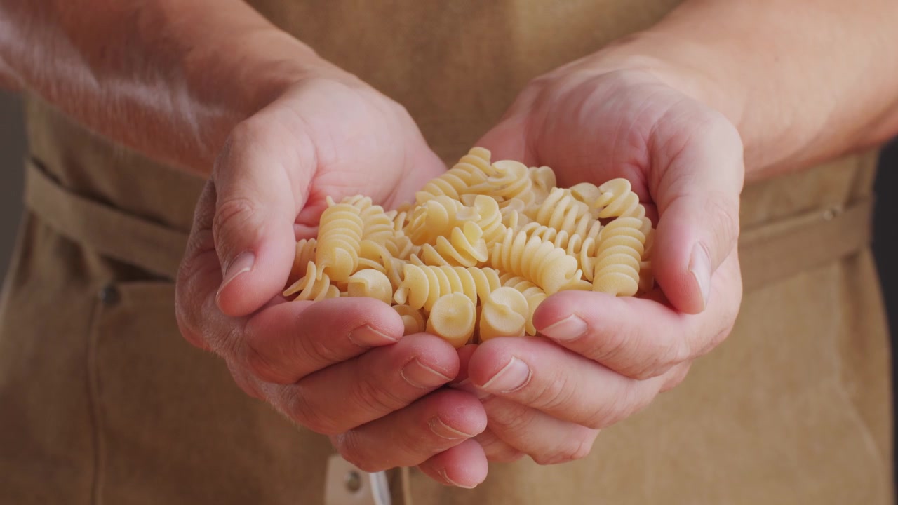 Close-up of Hands Holding Uncooked Spiral Pasta