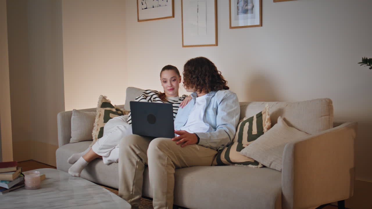 Couple discussing e-commerce store at laptop sitting comfortable apartment couch