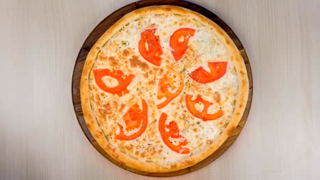pizza con tomates y queso en una tabla de madera.