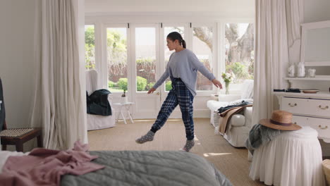 happy teenage girl practicing ballet dancing in bedroom rehearsing having fun dance on weekend morning wearing pajamas