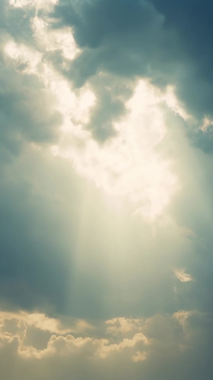 Vertical video: Sun pushing through cumulus gap opening casting beams over lit low bank from ground