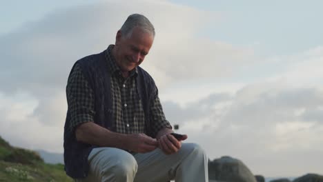 Un-Hombre-Mayor-Usando-Su-Teléfono-Móvil-Mientras-Está-Sentado-En-Un-Banco