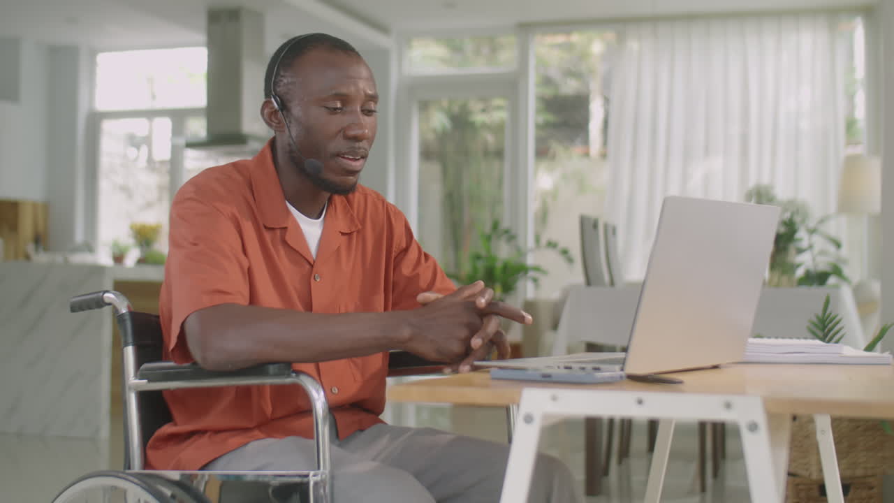 Uomo in sedia a rotelle che effettua una chiamata web su un laptop