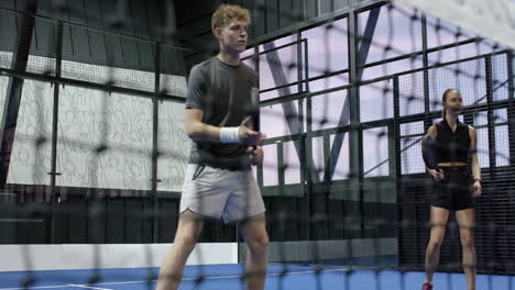 Diverse players engaging in intense padel tennis match on indoor court, focusing on action