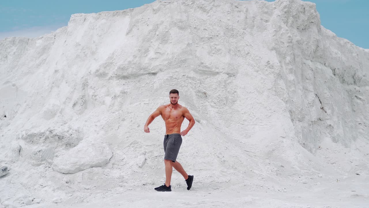 Young bodybuilder poses in nature. Handsome bodybuilder with perfect muscular body posing outdoors