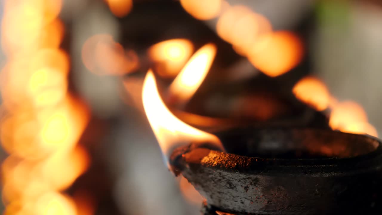 closeup 4k video de larga fila de lámparas de aceite ardiendo con fuego sagrado en el templo hindú