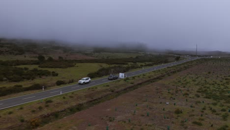 Aerial view of a car driving along a winding road near Pico do Areeiro and Pico das Torres in Madeira, Portugal, on a cloudy day