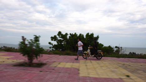 side shot of a woman riding a motorcycle in vietnam with a clear view of the ocean in the background