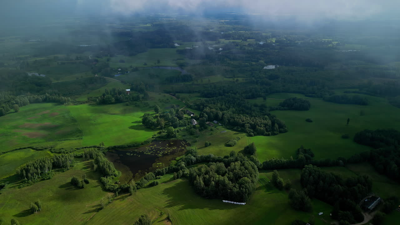 vídeo de drones de nubes bajas sobre bosques y granjas en zonas rurales