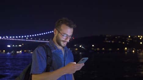 Man-looking-around-smiling-and-texting.-Night.