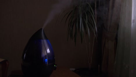 steam from a modern air humidifier in dark room. close-up, no people.