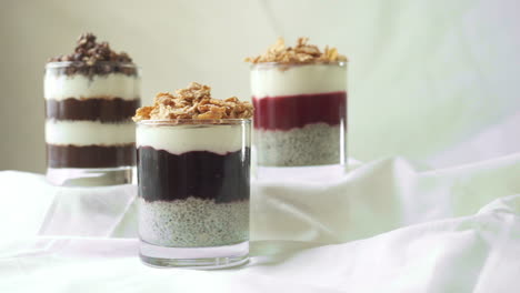 selection of layered chia puddings with hand taking one and putting it back